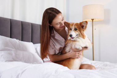 Evcil hayvan dostu otel. Yatağında tatlı Galli Corgi köpeği olan bir kadın.