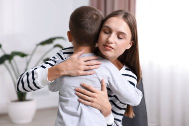 Anne, üzgün oğlunu evde destekleyip kucaklıyor.