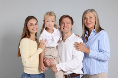 Aydınlık bir arkaplanda oğlu ve ailesi olan yaşlı bir kadının portresi.