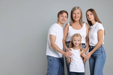 Açık gri arka planda, oğlu ve ailesiyle birlikte son sınıf öğrencisi bir kadının portresi. Metin için boşluk
