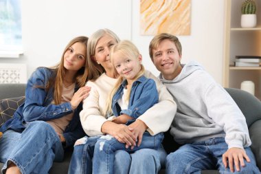 Oğlunun ailesiyle birlikte evdeki kanepede oturan yaşlı kadın.