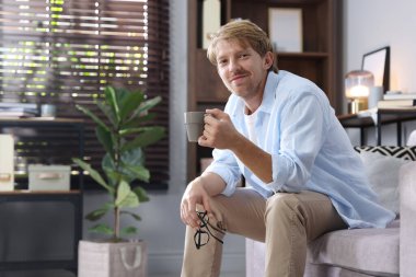 İçkili bir adam evdeki kanepede oturuyor, mesaj için yer var.