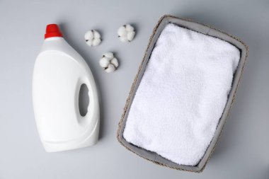 Bir şişe yumuşatıcı, havlu ve pamuk çiçekleri açık gri arka planda, düz yatıyordu.