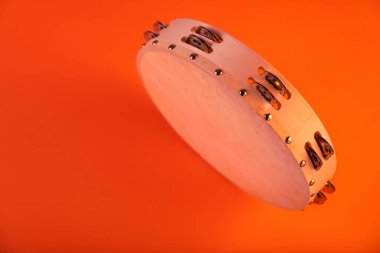 Tambourine on orange background. Space for text
