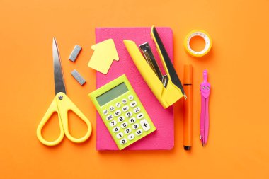 Zımba ve turuncu arka plandaki diğer kırtasiye malzemeleri, düz yatıyordu.