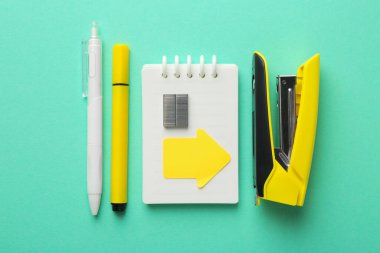 Stapler and other stationery on turquoise background, flat lay