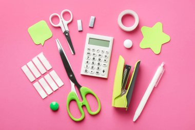 Stapler and other stationery on pink background, flat lay