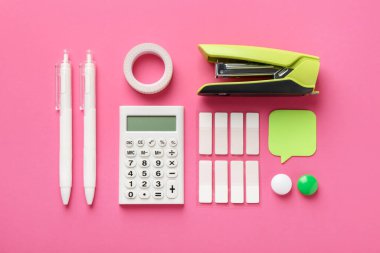 Stapler and other stationery on pink background, flat lay