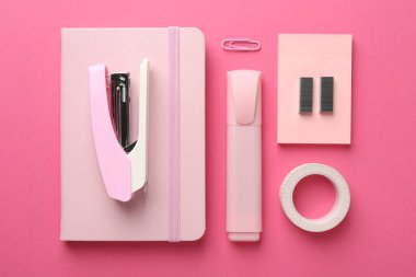 Stapler and other stationery on pink background, flat lay