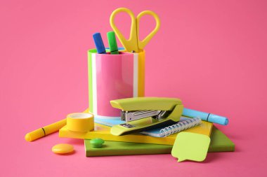 Stapler and other stationery on pink background