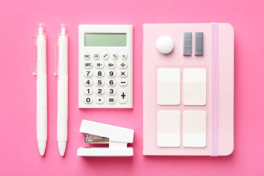 Stapler and other stationery on pink background, flat lay