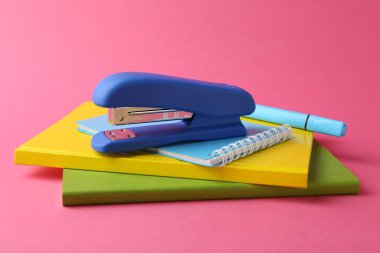 Stapler and other stationery on pink background