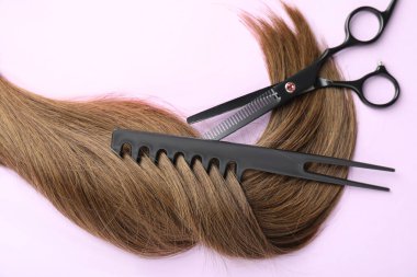 Güzel kahverengi saçlar, makas ve açık mor arkaplan tarağı, üst görünüm