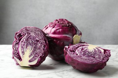 Whole and cut red cabbages on white marble table