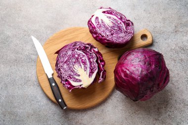 Whole and cut red cabbages with knife on grey table, flat lay