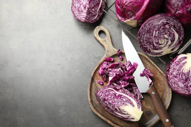 Fresh red cabbages and knife on grey table, flat lay. Space for text