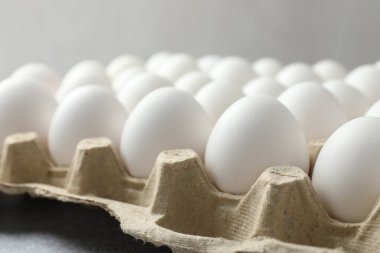 Yumurta kutusunda çiğ tavuk yumurtası. Gri masada, yakın plan.