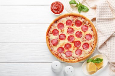 Delicious pepperoni pizza and ingredients on white wooden table, flat lay. Space for text