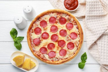 Delicious pepperoni pizza and ingredients on white wooden table, flat lay