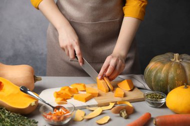 Gri masada balkabağı kesen kadın, yakın plan.