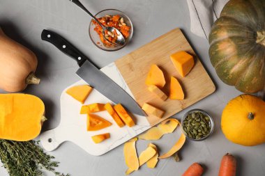 Fresh pumpkins, seeds and knife on light grey table, flat lay