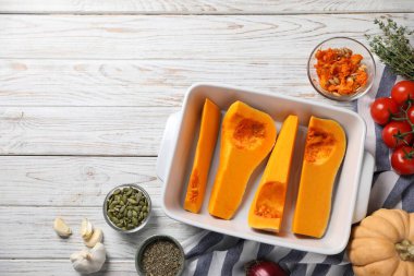 Balkabağını fırın tabağında doğra ve ahşap masada malzemeler var, düz yat. Metin için boşluk