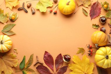 Flat lay composition with dry autumn leaves and pumpkins on pale orange background. Space for text