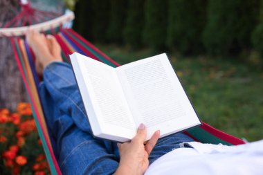Hamakta kitap okuyan son sınıf öğrencisi kadın, yakın plan.