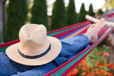 Hamakta dinlenen hasır şapkalı yaşlı kadın, yakın plan.