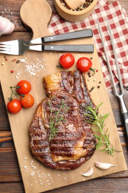 Delicious grilled beef steak with herbs, spices and products on wooden table, flat lay