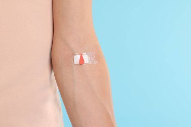 Kan bağışı. Kolunda açık mavi arka planda bandaj olan kadın, yakın plan. Metin için boşluk