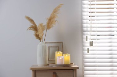 Decorative LED candles and other decor on wooden bedside table indoors