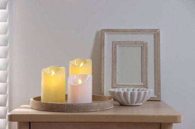 Decorative LED candles and other decor on wooden bedside table indoors