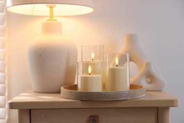 Decorative LED candles, vases and lamp on wooden table indoors