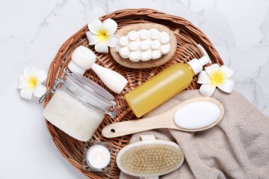 Flat lay composition with spa products and plumeria flowers on white marble table