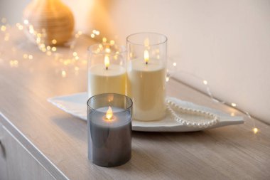 Dekoratif LED mumlar, inci kolye ve ahşap dolaptaki peri ışıkları, yakın plan.