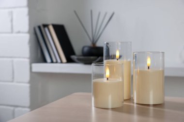 Decorative LED candles on wooden table at home, space for text