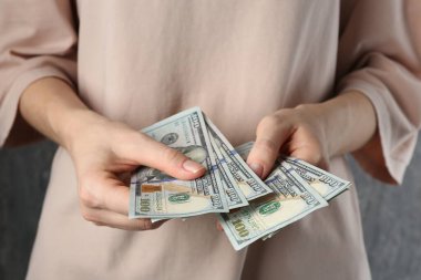Nafaka. Gri arka planda dolar banknotları olan kadın, yakın plan.