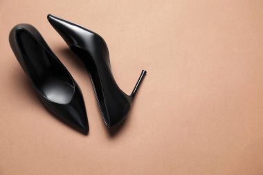 Pair of elegant black heels on brown background, top view with space for text. Stylish shoes