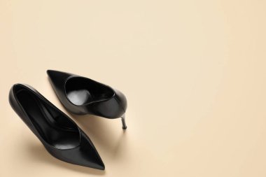 Pair of elegant black heels on beige background, top view with space for text. Stylish shoes
