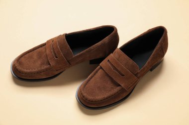 Pair of stylish chamois leather shoes on beige background