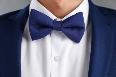 Gri arkaplanda şık papyonlu takım elbiseli adam, yakın plan.