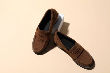 Pair of stylish brown shoes on beige background, above view