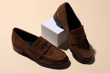 Pair of stylish brown shoes on beige background, closeup