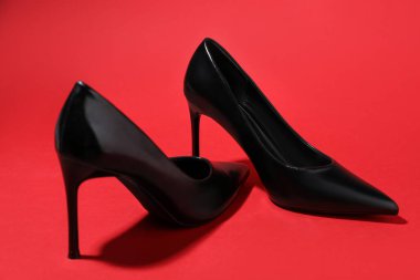 Pair of stylish high heeled shoes on red background, closeup