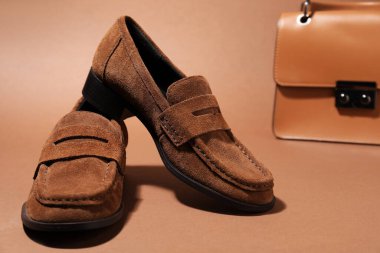 Pair of stylish brown shoes and bag on color background, closeup