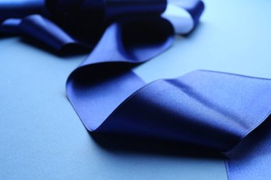 Beautiful blue ribbon on color background, closeup