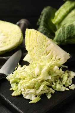 Shredded Savoy cabbage and knife on black table, closeup