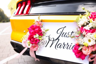 Düğün arabası. Cabriolet dekore edilmiş. Sadece evlilik kartı ve açık havada güzel çiçekler, yakın plan.