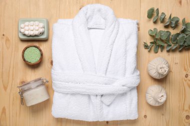 Flat lay composition with bathrobe and spa products on wooden table
